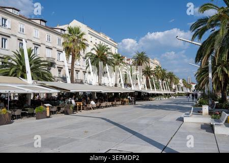 Split, Kroatien - 1. September 24: Palmengesäumte Uferpromenade Riva mit Caféterrassen in Split, Dalmatien, Kroatien an einem klaren, sonnigen Tag. Stockfoto