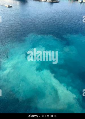 Hochwinkelaufnahme von leuchtendem türkisfarbenem und tiefblauem Meereswasser, das in der Nähe der Küste von Nassau, Bahamas, wirbelt. Stockfoto
