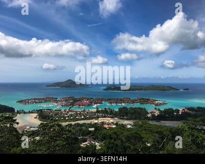 Erhöhter Panoramablick auf die luxuriöse Insel Eden, umgeben von atemberaubendem türkisfarbenem Meerwasser und üppig grünen tropischen Inseln im Hintergrund Stockfoto