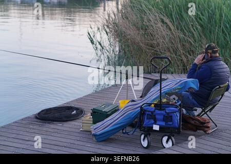 Fischer, die sich auf dem Holzpier an der Balatonfured Tagore Promenade am Balaton, Ungarn, entspannen. Stockfoto