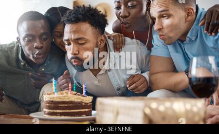 Kerzen, Blasen und Freunde mit Kuchen für Geburtstag, Party und Feier für eine Veranstaltung zu Hause. Happy, wish and man with Group for Social Meeting Stockfoto