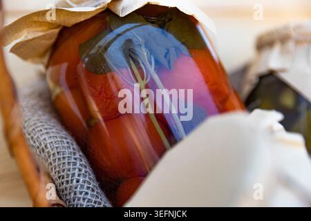 Hausgemachte Dosentomaten mit Basilikumblättern in rustikalem Glaskonservierungsglas Stockfoto