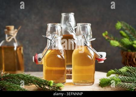 Flaschen mit hausgemachtem Kräutersirup, hergestellt mit jungen Fichtenspitzen, die im Frühjahr gesammelt werden Stockfoto