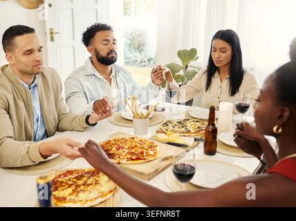 Freunde, betet und hält Hände zu Hause für Essen, verbindet sich und spirituelle christliche Gruppe. Menschen, Dankbarkeit und Anbetung Gott im Speisesaal für Stockfoto