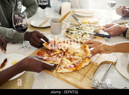 Pizza, Hände und eine Gruppe von Leuten zu Hause zum Essen, Binden und gemeinsamen Treffpunkt am Wochenende. Essen, Tisch und Freunde im Apartment mit Essen, Mittagessen oder Stockfoto