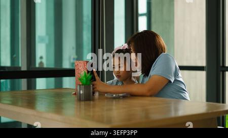 Asiatische Mutter und Tochter teilen sich den Smartphone-Bildschirm und sehen digitale Inhalte zusammen Stockfoto