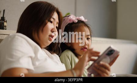 Mutter und Tochter verbinden sich zu Hause über Inhalte auf einem Smartphone Stockfoto