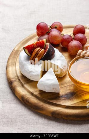Vorspeisenbrett mit Fleisch, Käse, Trauben, Nüssen, Honig und frischen Feigen. Charcuterie-Teller auf einer beigen Leinentischdecke. Stockfoto