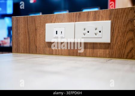 Nahaufnahme moderner Steckdosen, die auf einer Wandplatte aus Holz montiert sind, mit Standardsteckdosen und einem Schalter, geeignet für den Einsatz in Privathaushalten und im Büro Stockfoto