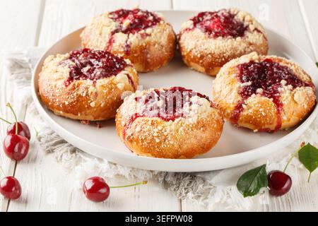 Hausgemachte offene Hefebötchen mit Kirschfüllung und Streusel in Nahaufnahme auf einem Teller auf einem Holztisch. Horizontal Stockfoto