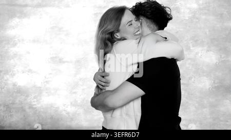 Junge Männer und Frauen umarmen sich liebevoll, zeigen Glück und Zweisamkeit Stockfoto