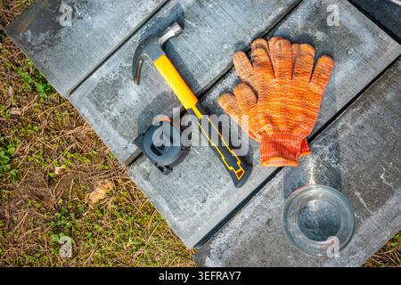 Hammer-Handschuhe und Maßband auf Betonblöcken im Freien, Detailansicht der Reparaturwerkzeuge. Konzept: Hausrenovierung Stockfoto