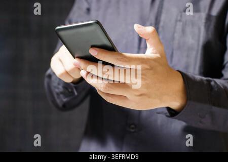 Mann, der ein Smartphone mit beiden Händen benutzt. Moderne Verbindung. Kommunikationsgerät. Geschäfts- und Technologiekonzept. Hochwertige Fotos Stockfoto