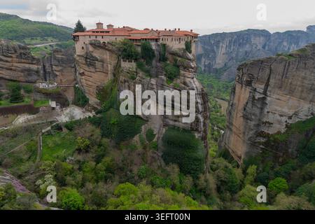 Ein beeindruckender Blick auf das Heilige Kloster von Varlaam, das auf einer massiven Felssäule sitzt, mit Blick auf die tiefgrünen Täler von Zentralgriechenland. Stockfoto