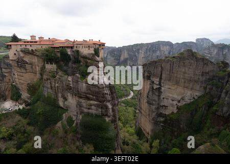 Ein beeindruckender Blick auf das Heilige Kloster von Varlaam, das auf einer massiven Felssäule sitzt, mit Blick auf die tiefgrünen Täler von Zentralgriechenland. Stockfoto