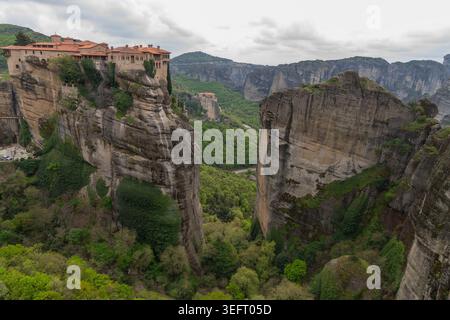 Ein beeindruckender Blick auf das Heilige Kloster von Varlaam, das auf einer massiven Felssäule sitzt, mit Blick auf die tiefgrünen Täler von Zentralgriechenland. Stockfoto