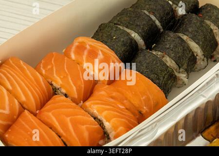 Lachs-Sushi-Brötchen und Nori-Maki in einem Take-out-Behälter Stockfoto