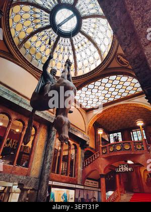 Prag, Tschechische Republik, 12.04.2023: Umgedrehte Pferdeskulptur von David Cerny im Lucerna-Palast. Verziertes Innenhof mit einem großen bronzenen Pferd-A Stockfoto