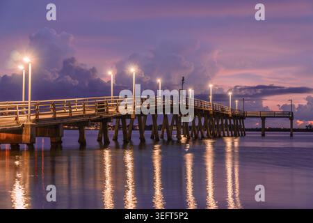 Dramatischer Sonnenuntergang mit violettem Himmel und Wolken über dem Angelpier in Sarasota Bay Florida Stockfoto