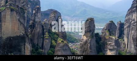 Ein atemberaubender Panoramablick auf die hoch aufragenden Felssäulen von Meteora, mit dem Dorf Kastraki, eingebettet in das grüne Tal darunter. Stockfoto