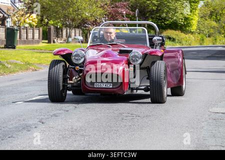 Ein kastanienbrauner Tiger Super Cat Sportwagen fährt an einem sonnigen Tag entlang einer Wohnstraße in Großbritannien zur Renntag Car Show 2026. Stockfoto