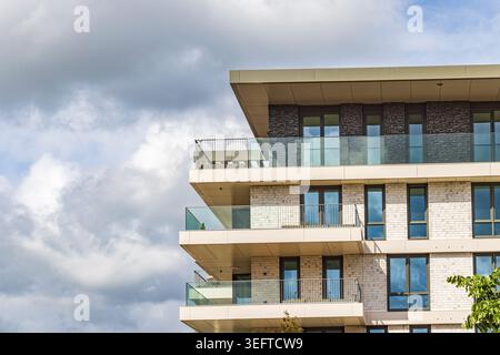 Moderner Wohnblock mit Glasbalkonen mit Blick auf Bäume in einem Vorstadtgebiet von Ede, Niederlande. Ruhiges urbanes Leben, Architektur Stockfoto