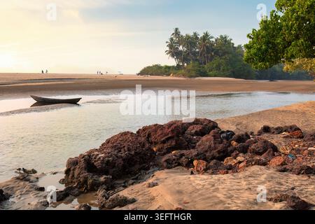 Pittoresker Sonnenuntergang mit Kanu und Palmen in der Nähe von Anjuna Beach im Norden Goas, Indien Stockfoto
