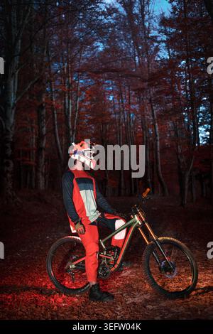Radfahrer posieren mit dem Mountainbike in der Nacht im Herbstwald Stockfoto