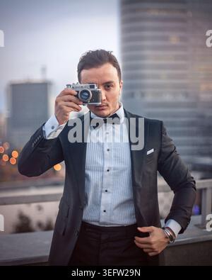 Eleganter Mann, der die Stadt mit einer alten Kamera fotografiert Stockfoto
