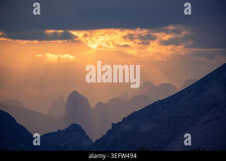 Sonnenstrahlen brechen durch Wolken über Berglandschaft Stockfoto