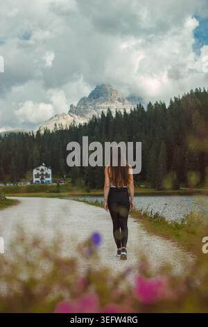 Frau, die auf dem Landweg des Sees in den dolomiten läuft Stockfoto