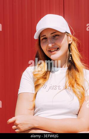 Junge Frau lächelt in weißer Mütze und T-Shirt Stockfoto