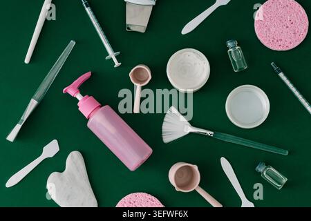 Trendiges Hautpflegemuster mit Reinigungswerkzeugen, Kosmetikaccessoires und Essentials für Spa auf grünem Hintergrund. Hautpflege und Schönheitsidee. Stockfoto