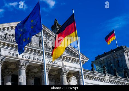 Deutsche und EU-Fahnen winken vor dem Reichstagsgebäude und der Inschrift „dem Deutschen Volke“ in Berlin. Stockfoto