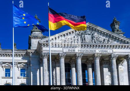 Deutsche und EU-Fahnen winken vor dem Reichstagsgebäude und der Inschrift „dem Deutschen Volke“ in Berlin. Stockfoto
