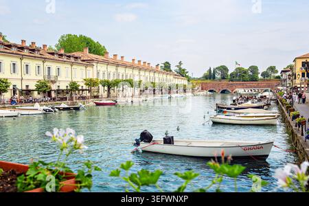 Peschiera del Garda, Italien - 30. April 2026: Malerischer Blick auf den Kanal in Peschiera del Garda mit Booten, historischer Architektur und lebhaftem Grün Stockfoto