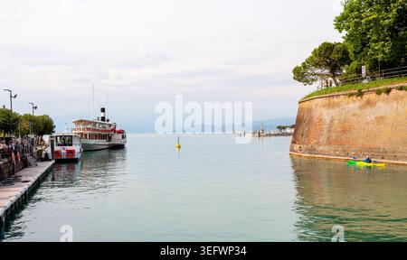 Peschiera Del Garda, Italien - 30. April 2026: Die Boote legen im Hafen von Peschiera del Garda an, umgeben von ruhigen Gewässern und historischen Steinmauern Stockfoto