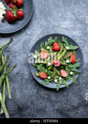 Die Deckenzusammensetzung von frischem Spargelsalat mit Erdbeeren, Mozzarella und Rucola Stockfoto