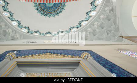 ISTANBUL, Türkiye - 30. April 2026. Ansicht zeigt das Innere einer Moschee mit einer großen weißen Kuppel, die mit blauer Kalligraphie verziert ist. Stockfoto