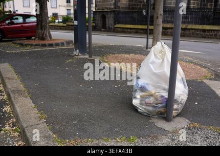 Weißer Plastikmüllsack voller Abfall auf einem Bürgersteig in Clermont-Ferrand, Frankreich. Stockfoto