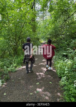 Ein Mann und eine Frau wandern in einem Wald in der Nähe von Eugene, Oregon, von hinten gesehen. Stockfoto