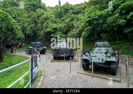 Ausstellung von gepanzerten Fahrzeugen im Hong Kong Museum of Coastal Defence – Militärausstellung im Freien in üppiger Umgebung am Hügel Stockfoto