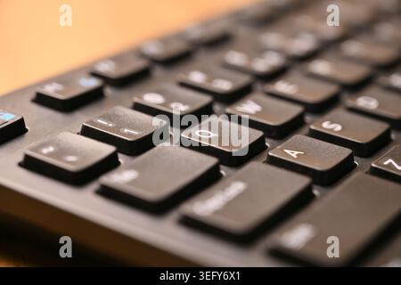 Schwarze Computertastatur Makroaufnahme mit Q-Taste und weichem, verschwommenem Hintergrund, angewinkelte Ansicht von oben Stockfoto