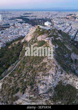 Ein vertikales Luftbild der St. George Kapelle auf dem Lycabettus Hügel mit Blick auf das Stadtzentrum von Athen und die Akropolis während des frühen Morgenlichts. Stockfoto
