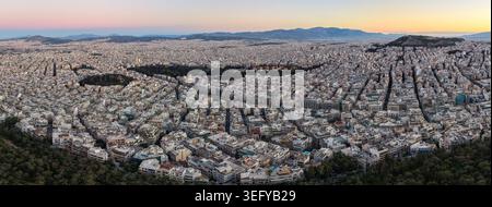 Ein Panorama-Luftbild der weitläufigen Stadt Athen, Griechenland, zeigt die dichte Architektur und Berge bei einem sanften Sonnenaufgang bei Sonnenaufgang. Stockfoto