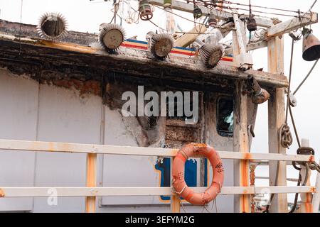 Yilan, Taiwan - 31. März 2025: Rußbedecktes Radhaus eines feuerhädigten Trawlers in Nanfangao, mit zersplitterten Fenstern und einem Rettungsring am Geländer. Stockfoto