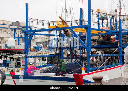Yilan, Taiwan - 31. März 2025: Die Besatzung der Migranten organisiert Schleppnetze an Bord eines blauen Fischereifahrzeugs im Hafen von Nanfangao, um sich auf die Abfahrt vorzubereiten. Stockfoto