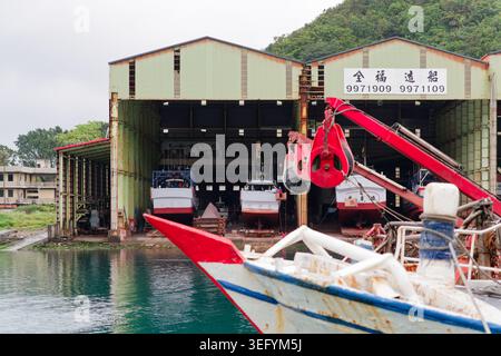 Yilan, Taiwan - 31. März 2025: Chen FWU Shipbuilding Co. In Nanfangao mit Schiffen, die für Seeversuche bereit sind, und einem roten Kran im Vordergrund. Stockfoto