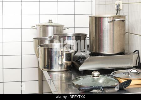 Große Töpfe aus Edelstahl auf der Arbeitsplatte in einer gewerblichen Küche, professionelles Kochgeschäft, Kopierraum, ausgewählter Fokus, geringe Schärfentiefe Stockfoto