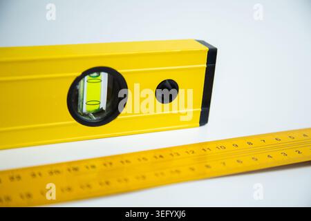 Nahaufnahme der Ebene und des Messlinals liegen auf weißem Hintergrund. Das Konzept der flachen Oberfläche Stockfoto